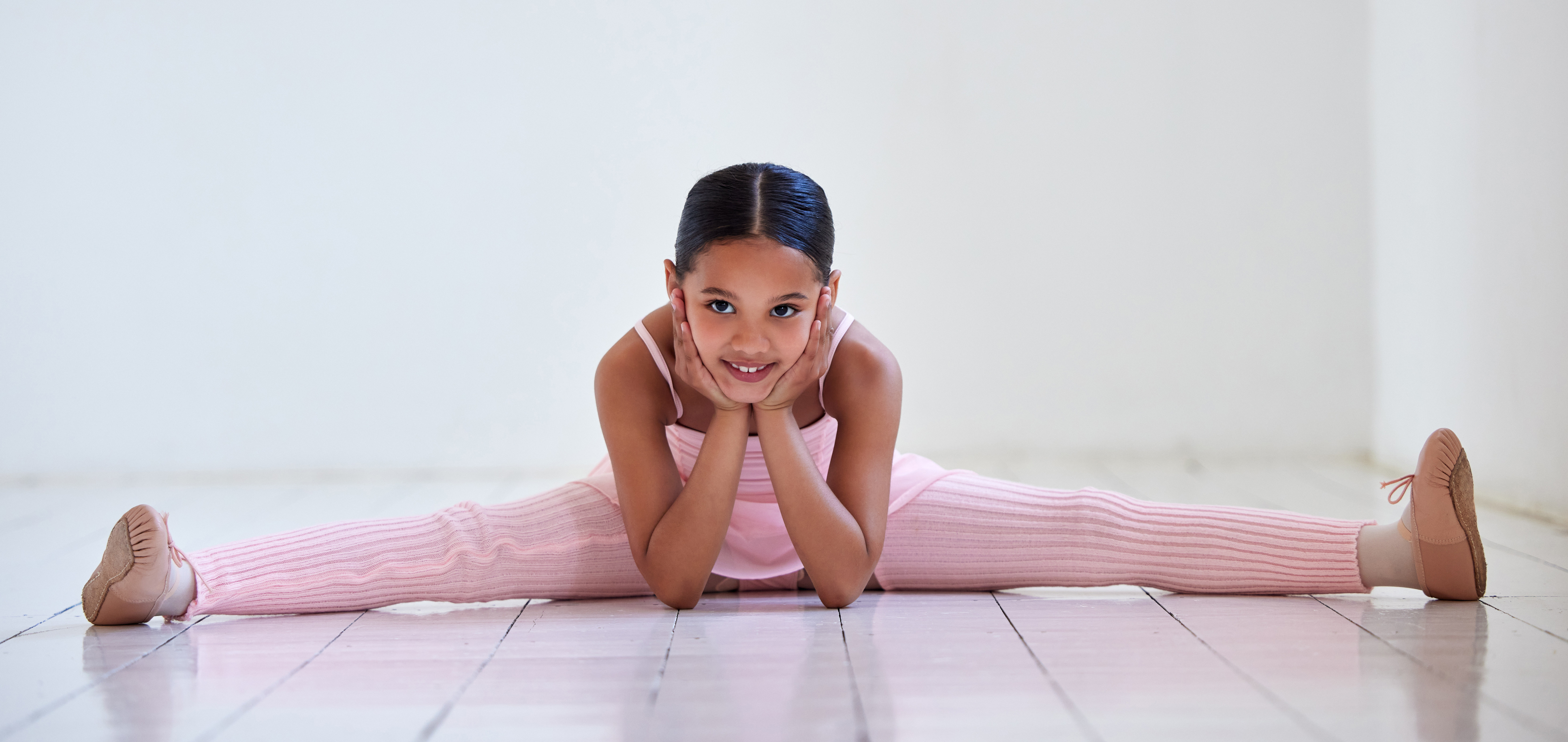 Niña en split sonriendo en el estudio de ballet