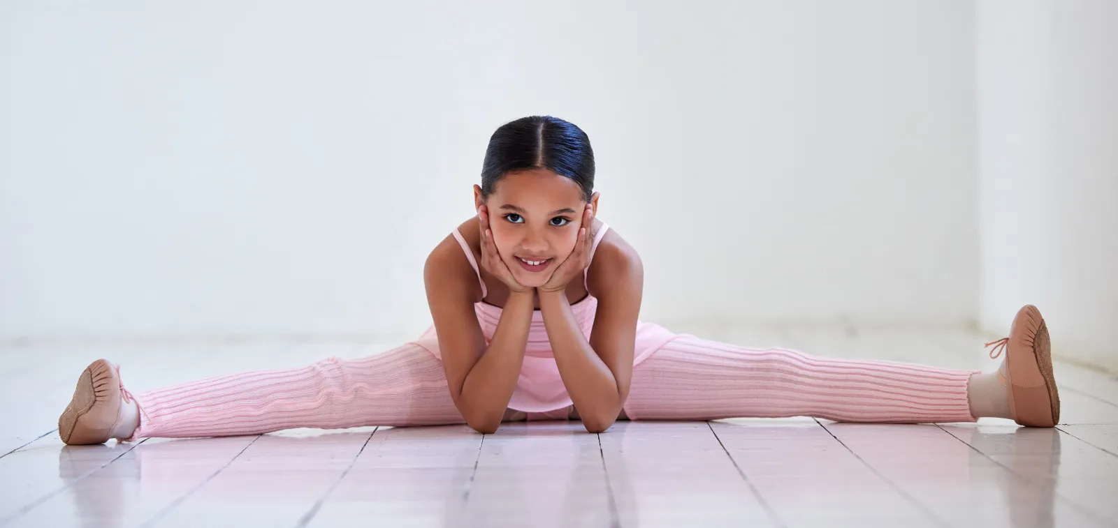 Niña en split sonriendo en el estudio de ballet